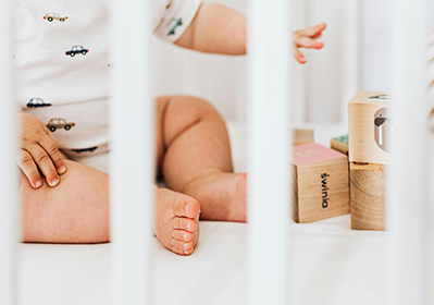 Baby in a crib playing with blocks.