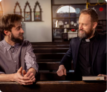Two men talking in pews of a traditional church
